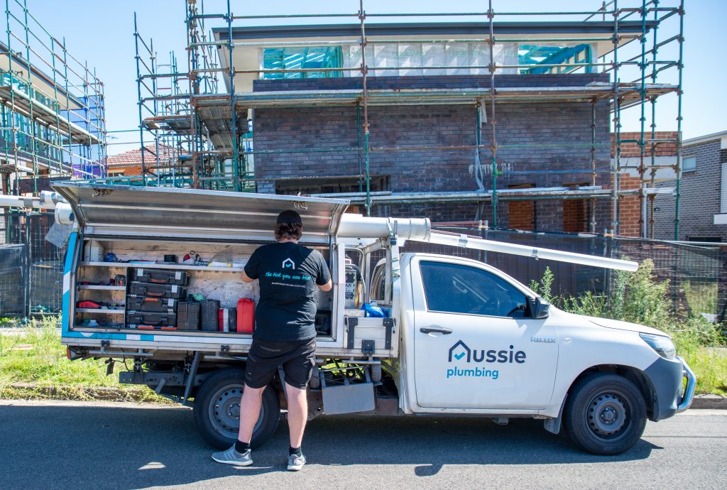 A plumber getting his tools from Aussie Electrical and Plumbing service van.